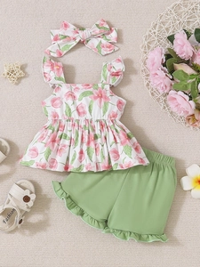 Flat lay of baby girl floral top, green ruffle shorts, and matching bow headband