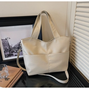 Detailed view of cream PU leather tote bag with front pocket in a lifestyle setting