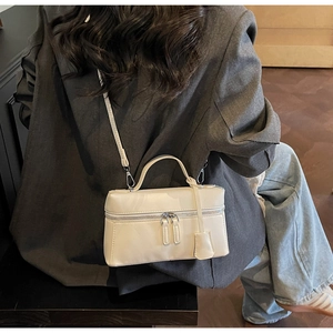 Photo de style de vie du petit sac carré crème porté avec un costume gris par un modèle