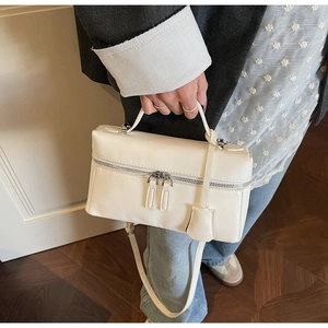Détail d'un sac à bandoulière en cuir blanc avec double fermeture éclair et bandoulière