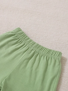 Detail of baby mint green pants featuring a soft elastic waistband and ribbed knit texture