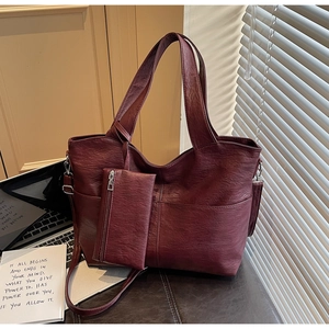 Deep red textured leather tote bag with matching zippered pouch and shoulder strap detail