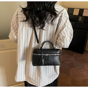 Détail d'un sac à main boîte en cuir noir avec ferrures argentées et bandoulière