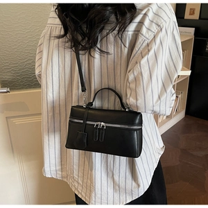 Sac bandoulière noir rectangulaire chic avec fermetures argentées sur un mannequin