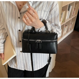 Détail d'un sac boîte carré noir avec double fermeture éclair et pendentif assorti