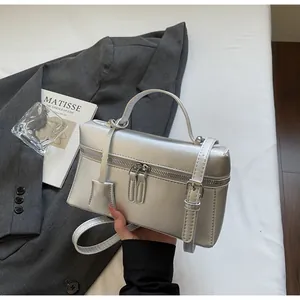 Détail d'un sac à main carré argenté avec double fermeture éclair sur drap blanc