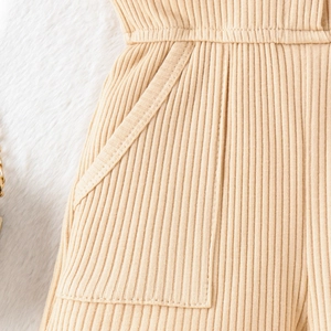Dettaglio macro della trama a coste beige e della tasca laterale della tutina per bambini