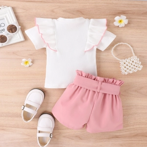 Details des Sommermädchen-Sets mit weißem Oberteil, Rüschenärmeln und rosa Shorts