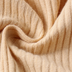 Dettaglio della trama del tessuto a maglia a coste beige di una tuta da bambino