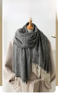 Détail d'une écharpe d'hiver à carreaux gris et blancs avec franges sur un mannequin