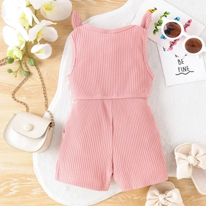 Dettaglio di una tutina rosa a costine senza maniche per bambina su legno
