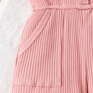 Dettaglio del tessuto a maglia a coste rosa e tasca laterale della tuta da bambina