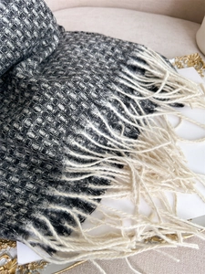Détail de l'écharpe à carreaux noir et blanc avec de longs pompons blancs et texture