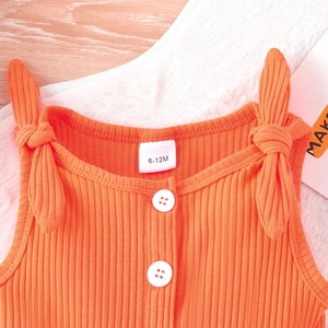 Dettaglio tutina neonato arancione a coste con etichetta 6-12M e spalline a fiocco