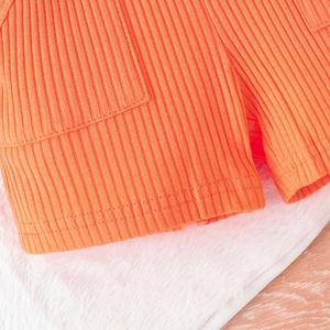 Dettaglio macro del tessuto a costine arancione con texture elastica e cuciture piatte fini