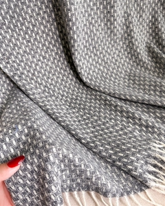 Détail d'une écharpe en maille grise et beige avec texture tissée et bords frangés