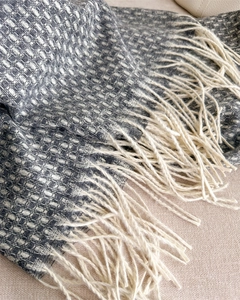 Gros plan d'une écharpe en cachemire gris et blanc avec tissage épais et longs franges