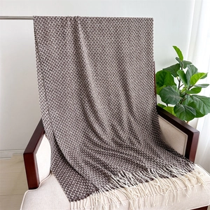 Détail d'une écharpe à carreaux marron doux avec franges crème sur une chaise en bois