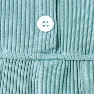 Dettaglio macro del tessuto a costine verde menta con bottone bianco e cuciture precise