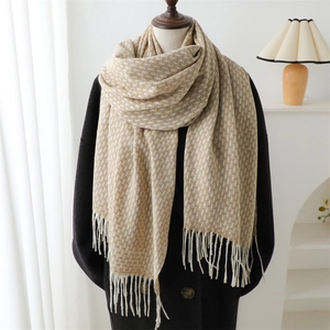Écharpe élégante beige à motif jacquard géométrique et franges sur un manteau en laine noir