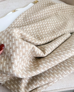 Gros plan sur la texture détaillée du tissu d'écharpe tissé beige et blanc doux