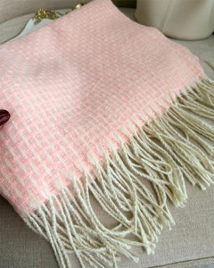 Vue détaillée d'une écharpe tissée rose et blanche avec des franges sur fond beige doux