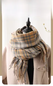Detail shot of winter plaid scarf with fringe tassels on a beige coat background