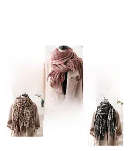 Close-up of fringe details on plaid cashmere-feel scarves in pink, brown and grey