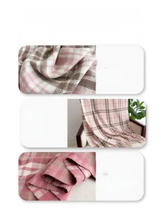 Close-up of pink and beige plaid scarf showing soft cashmere-like texture and tassel detail