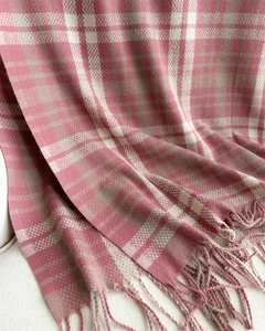 Detailed view of pink plaid scarf with fringe texture and soft knit pattern