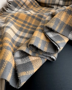 Close-up of yellow and grey plaid scarf fabric texture with soft tassel edge details
