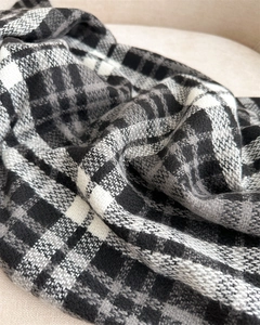 Close-up of classic black and gray plaid scarf fabric with soft cashmere texture and fringe