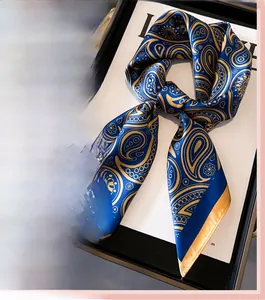 Détail d'un foulard carré luxe bleu marine effet soie avec motifs paisley dorés et satinés