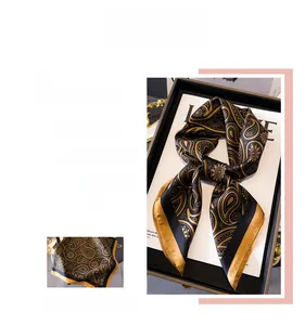Détail d'un foulard en soie de luxe avec motifs cachemire noir et or en satin brillant
