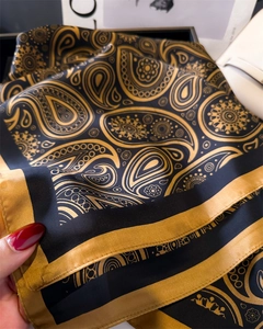 Gros plan d'un foulard en soie de luxe avec motif paisley noir et doré brillant
