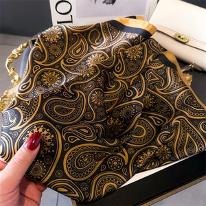 Vue détaillée d'un foulard en soie noire de luxe avec motifs cachemire dorés et texture