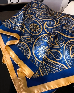 Détail de foulard en soie de luxe avec motifs paisley bleu et or et texture satin
