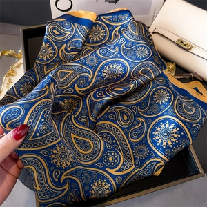 Détail d'un foulard en soie bleu marine avec des motifs cachemire dorés élégants