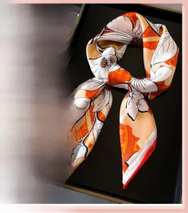 Detailed close-up of floral print silk scarf featuring elegant orange and beige patterns