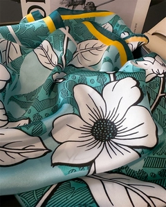Detail of silk-like lake green floral scarf showing smooth texture and yellow border