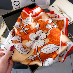 Detailed view of floral silk scarf with orange patterns and premium smooth texture