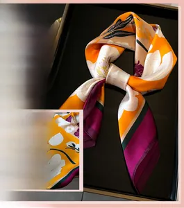 Gros plan d'un foulard en soie orange avec motif floral et bordures rayées