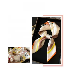 Vue détaillée d'un élégant foulard en soie aux motifs floraux orange et vert vifs