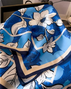 Close-up of royal blue floral silk scarf with elegant satin finish in a gift box