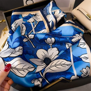 Detailed close-up of blue and white floral silk scarf with elegant satin finish on a tray