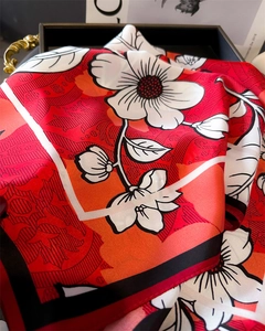 Close-up of elegant floral print silk square scarf in vibrant red and orange tones