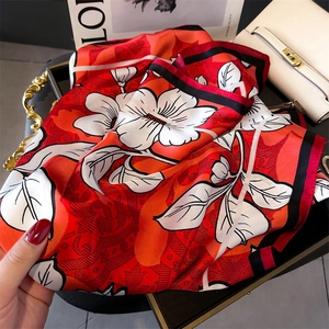 Detail of red floral silk scarf featuring elegant white flower patterns and satin texture