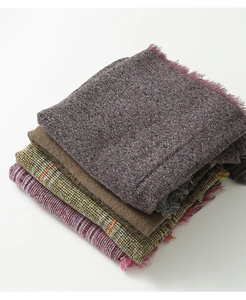 Détail de ponchos à carreaux empilés montrant le tissu doux effet cachemire et franges