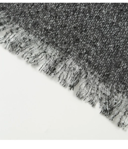 Gros plan d'un châle poncho gris avec texture tricotée épaisse et détails de franges