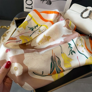 Gros plan d'un foulard en soie fleurie avec des bords roulés à la main orange vif